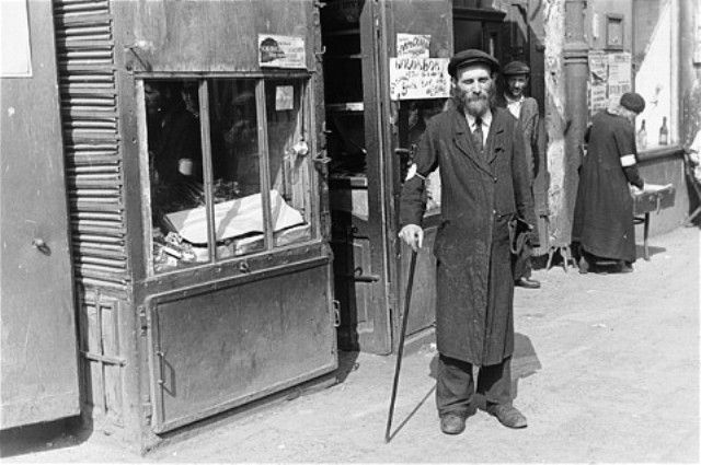 An Jewish man walks along a street in the Warsaw ghetto